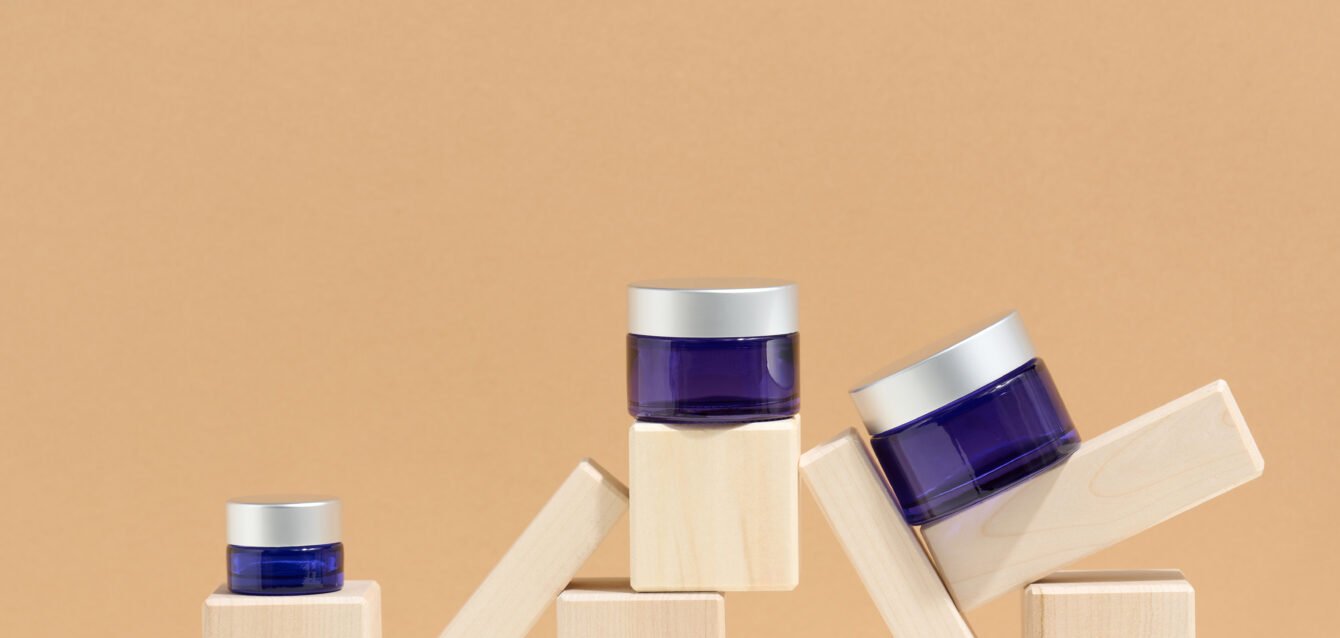 cosmetic products in a blue glass jar with a gray lid stand on a