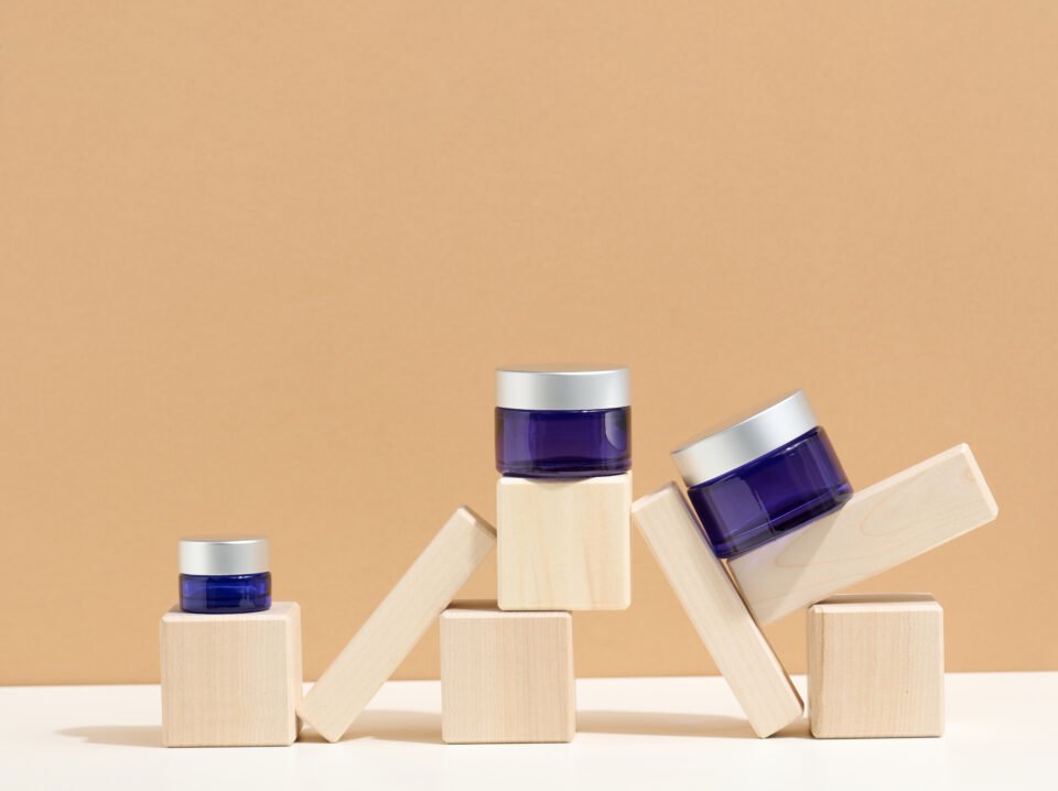 cosmetic products in a blue glass jar with a gray lid stand on a